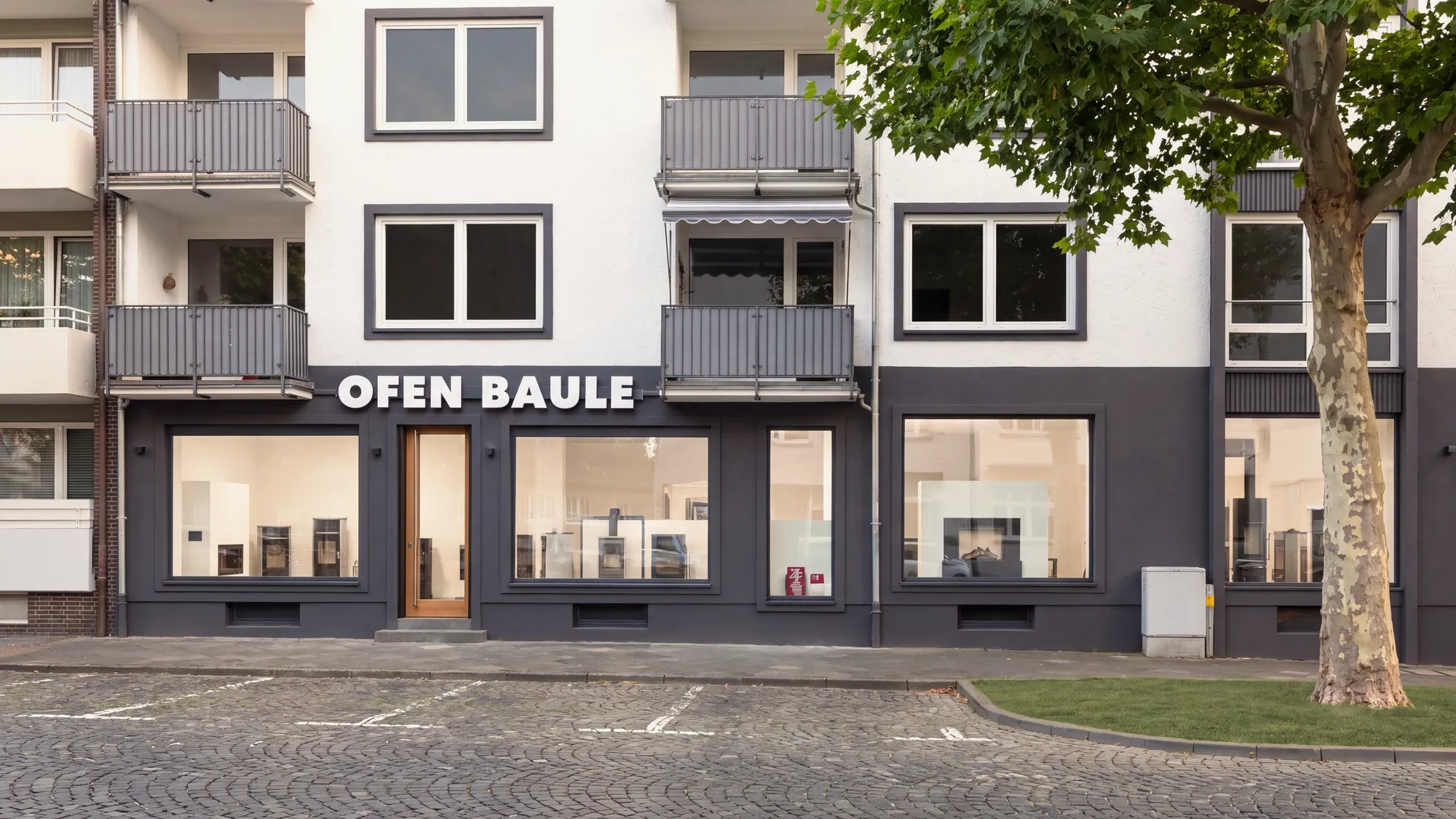 Die Ladenfront von Ofen Baule am Neustädter Markt 8 in Hildesheim: dunkelgraues Erdgeschoss mit großen Schaufenstern, darüber der weiße Schriftzug OFEN BAULE