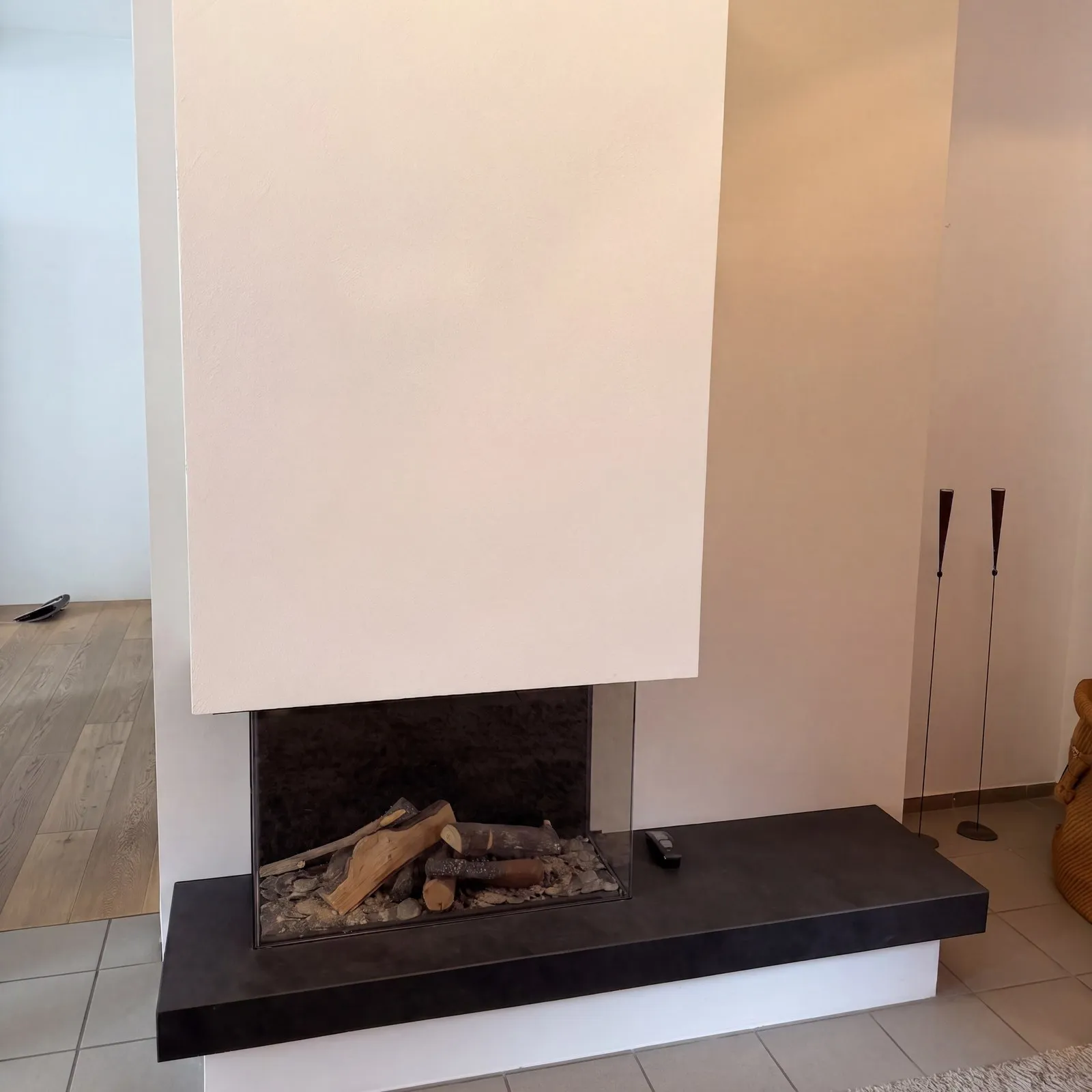 Weiß verputzter Kamin mit dunkler Steinbank